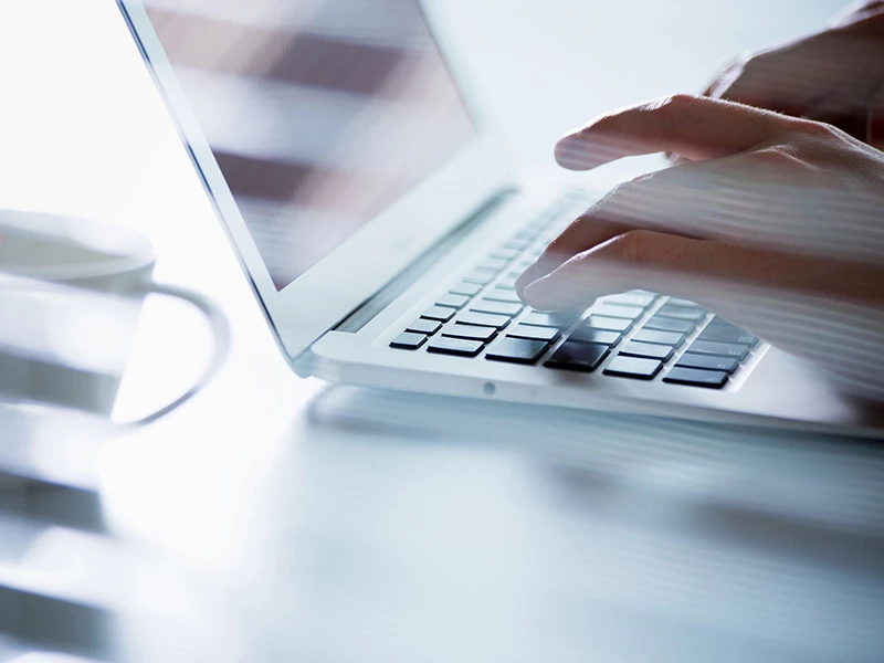 Close-up of hands typing on a laptop